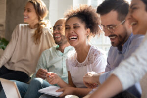 A diverse group of people laughing and engaging in a supportive discussion, representing the positive effects of DBT skills for depression in improving emotional well-being and relationships.