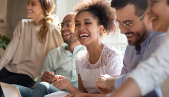 A diverse group of people laughing and engaging in a supportive discussion, representing the positive effects of DBT skills for depression in improving emotional well-being and relationships.